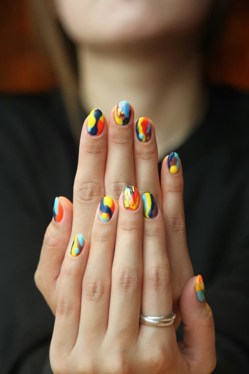 Two hands with multicoloured abstract nail art